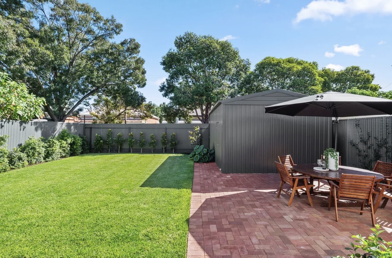 Yard Theory backyard with lawn, brick-paved dining patio and umbrella