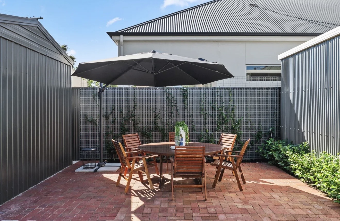 Brick courtyard with outdoor dining, umbrella and climbing plants